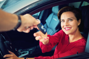 Car dealer is giving car key to a businesswoman